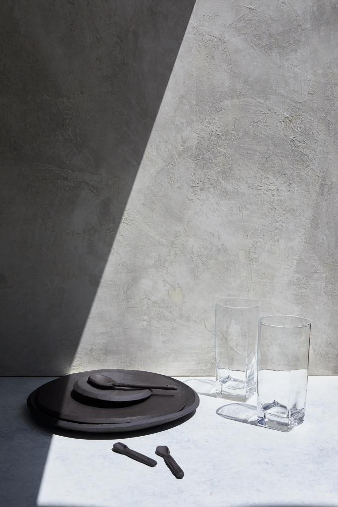 black-plate-two-glass-cups-white-table-with-shadow-falling-them.jpg